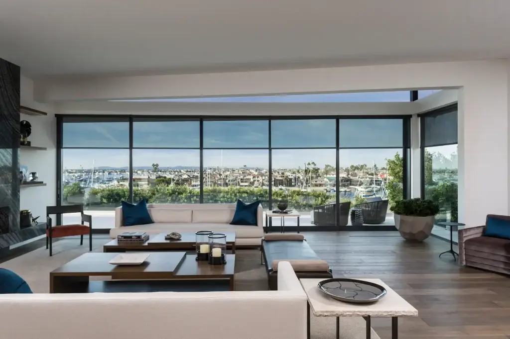 Savant motorized shades lowered over floor-to-ceiling living room windows